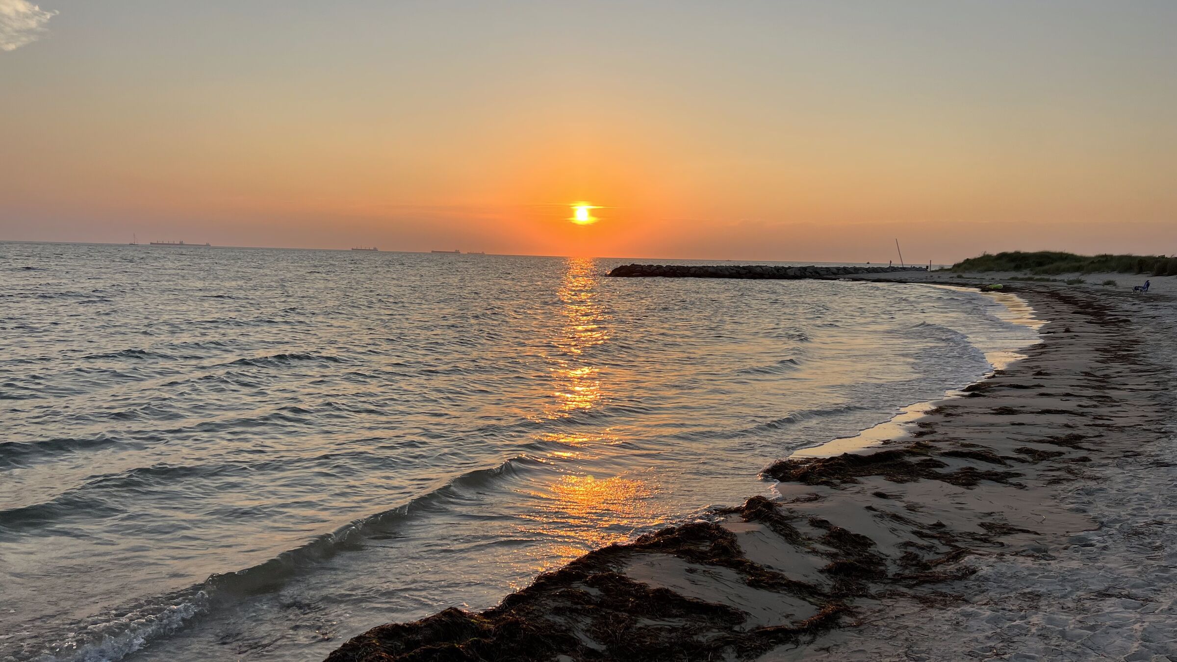 Sunset over calm Chesapeake Bay water and a sandy shoreline